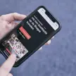 Hand houdt smartphone vast met een pagina over Brugse rondvaarten op het scherm.