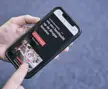 Hand houdt smartphone vast met een pagina over Brugse rondvaarten op het scherm.